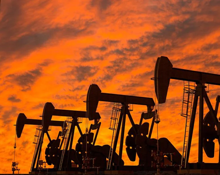 a group of oil rigs against a sunset
