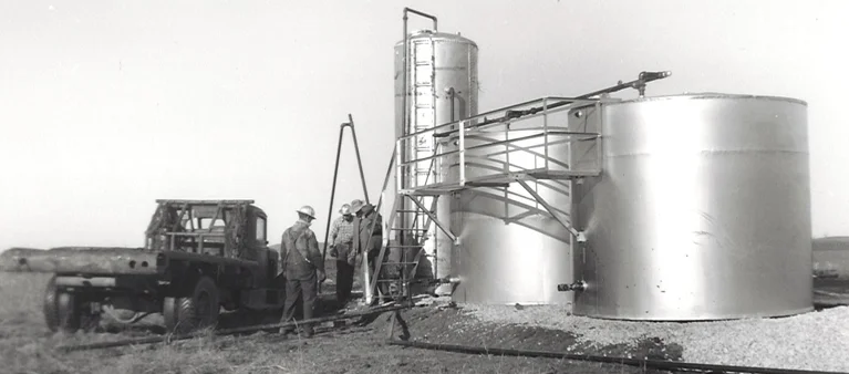 men standing next to a large silver tank