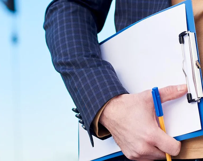 a person holding a clipboard and a pen
