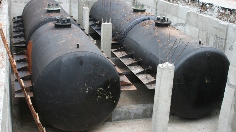 Four black large cylinder tanks for underground gasoline storage installed on construction site