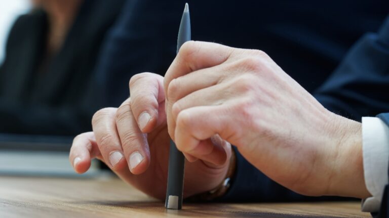 man holds a fountain pen while sitting at a table