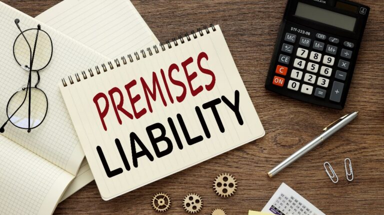 Glasses and a calculator lie on a notebook with words Premises liability