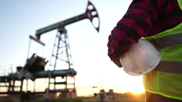 a worker holding a protective hard hat at sunset