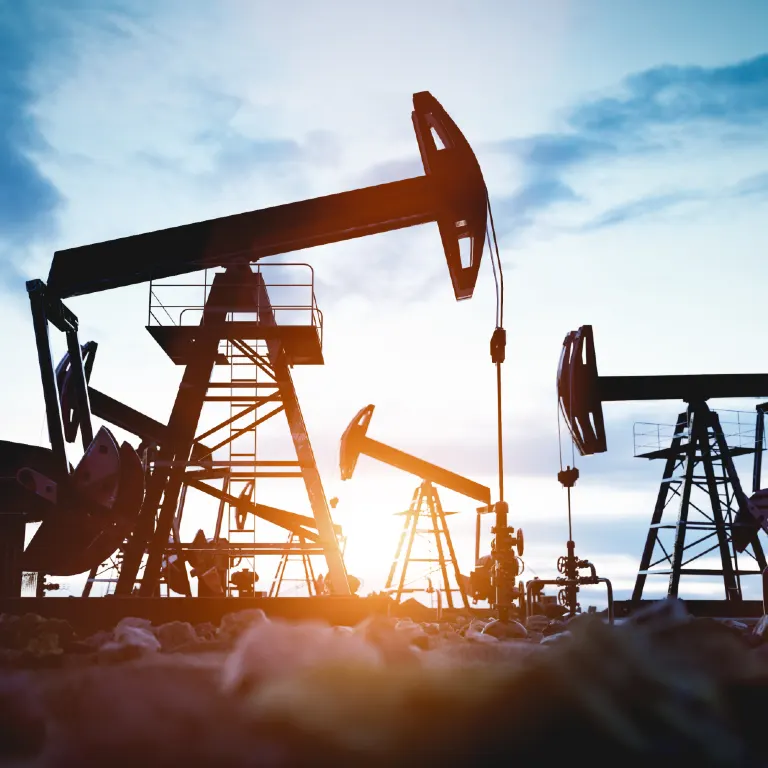 Oil pump jacks at sunset extracting crude oil.